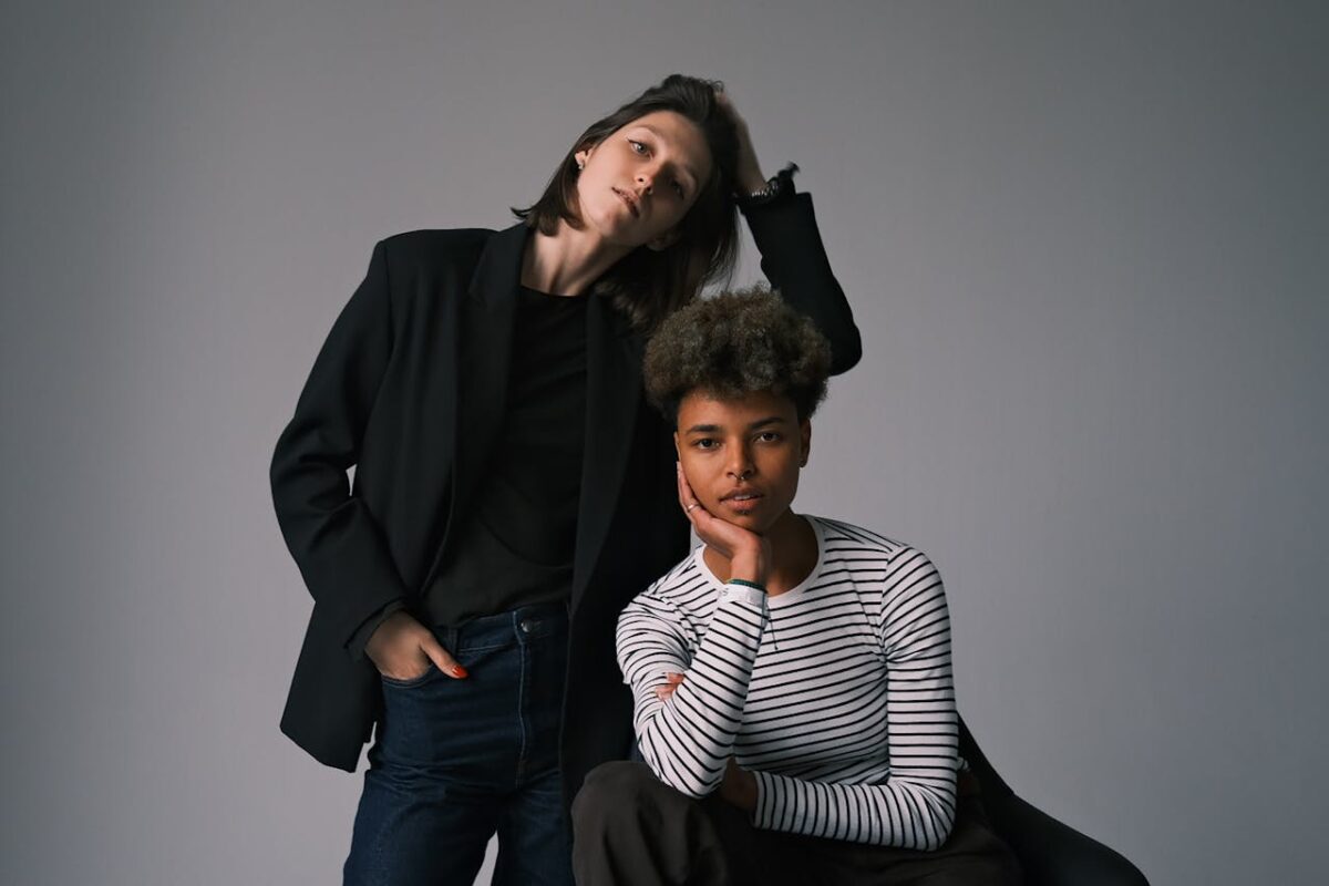 A modern portrait of two stylish adults in casual and elegant attire posing indoors.