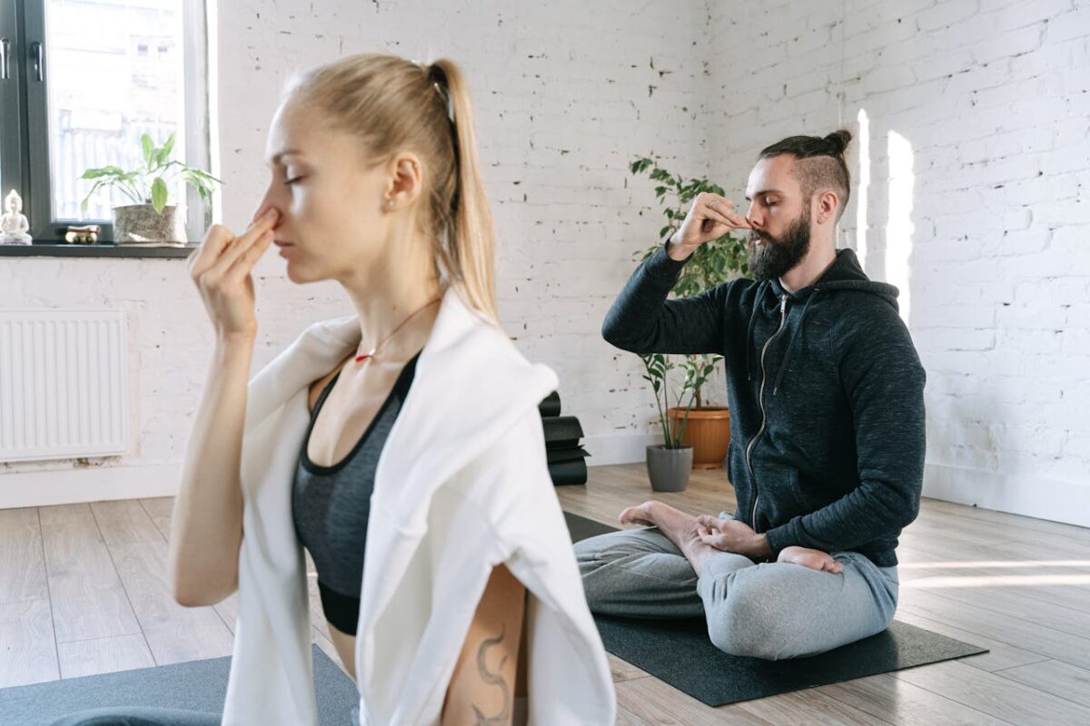A man and woman practicing mindful yoga and breathing exercises in a serene indoor setting.